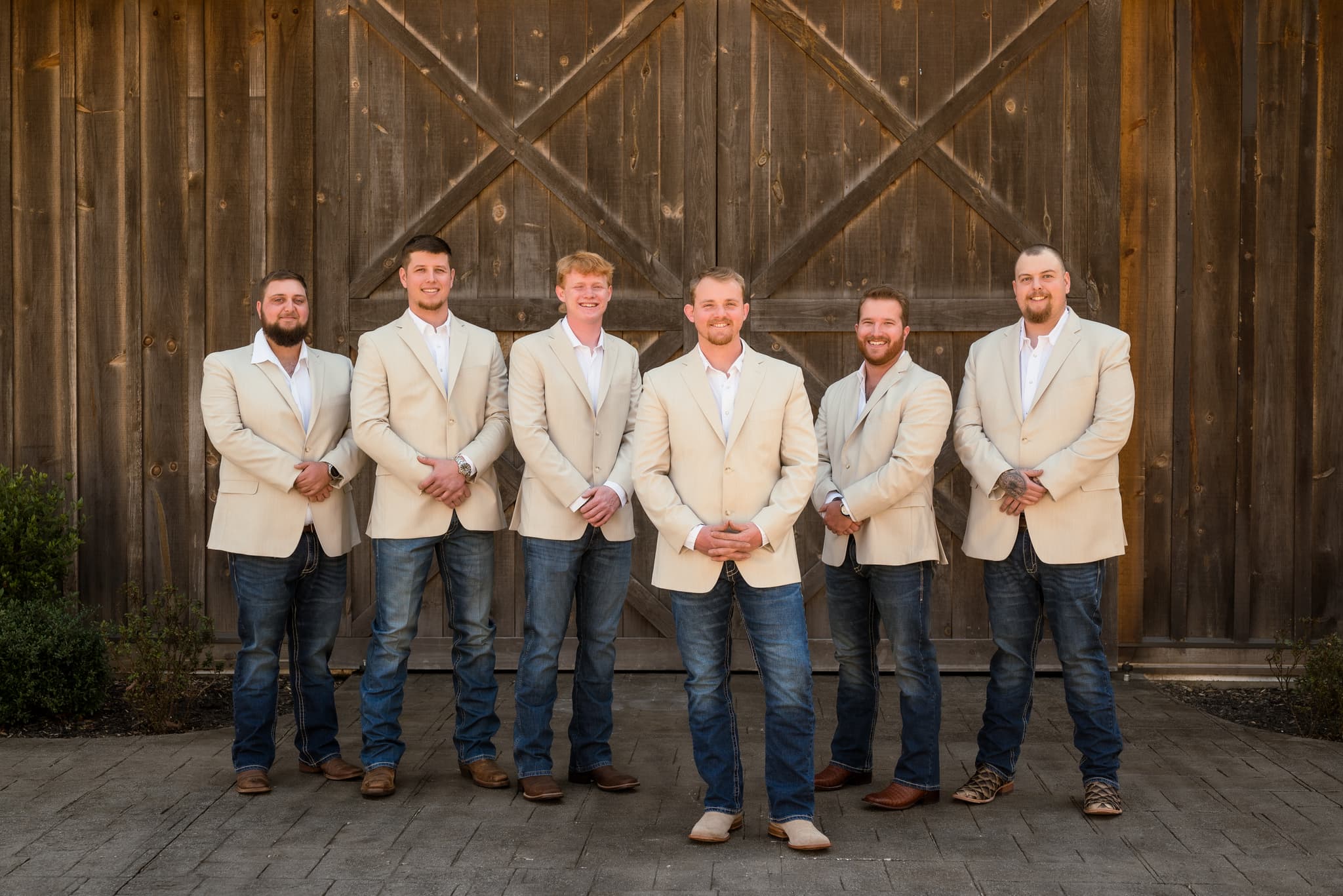 Groomsmen in tan blazers at a rustic barn venue